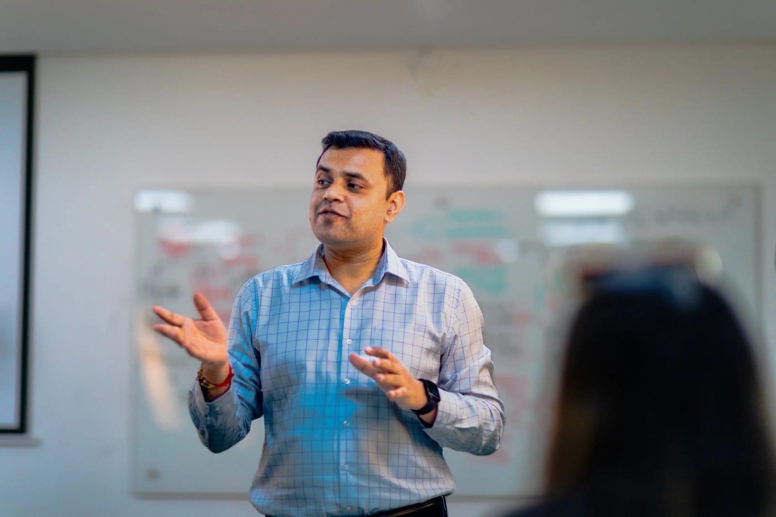 A mentor mid-session, speaking to a room with hands raised in explanation